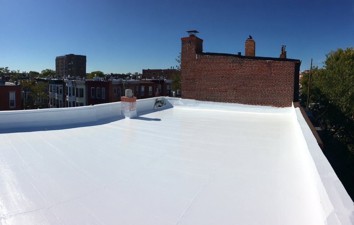 Bright white acrylic coating covering the seams of a Brooklyn commercial flat roof on a sunny day