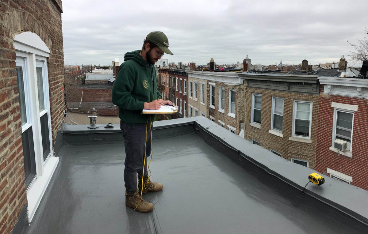 BST Roofers estimator measuring a Brooklyn flat roof before pricing a new white TPO membrane